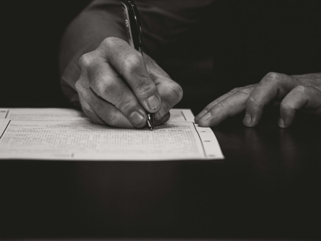 Homepage Monochrome image of a hand writing on a document, emphasizing attention to detail.